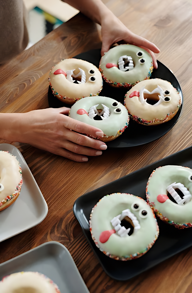 Hands placing down donuts decorated as monsters to match halloween decor.